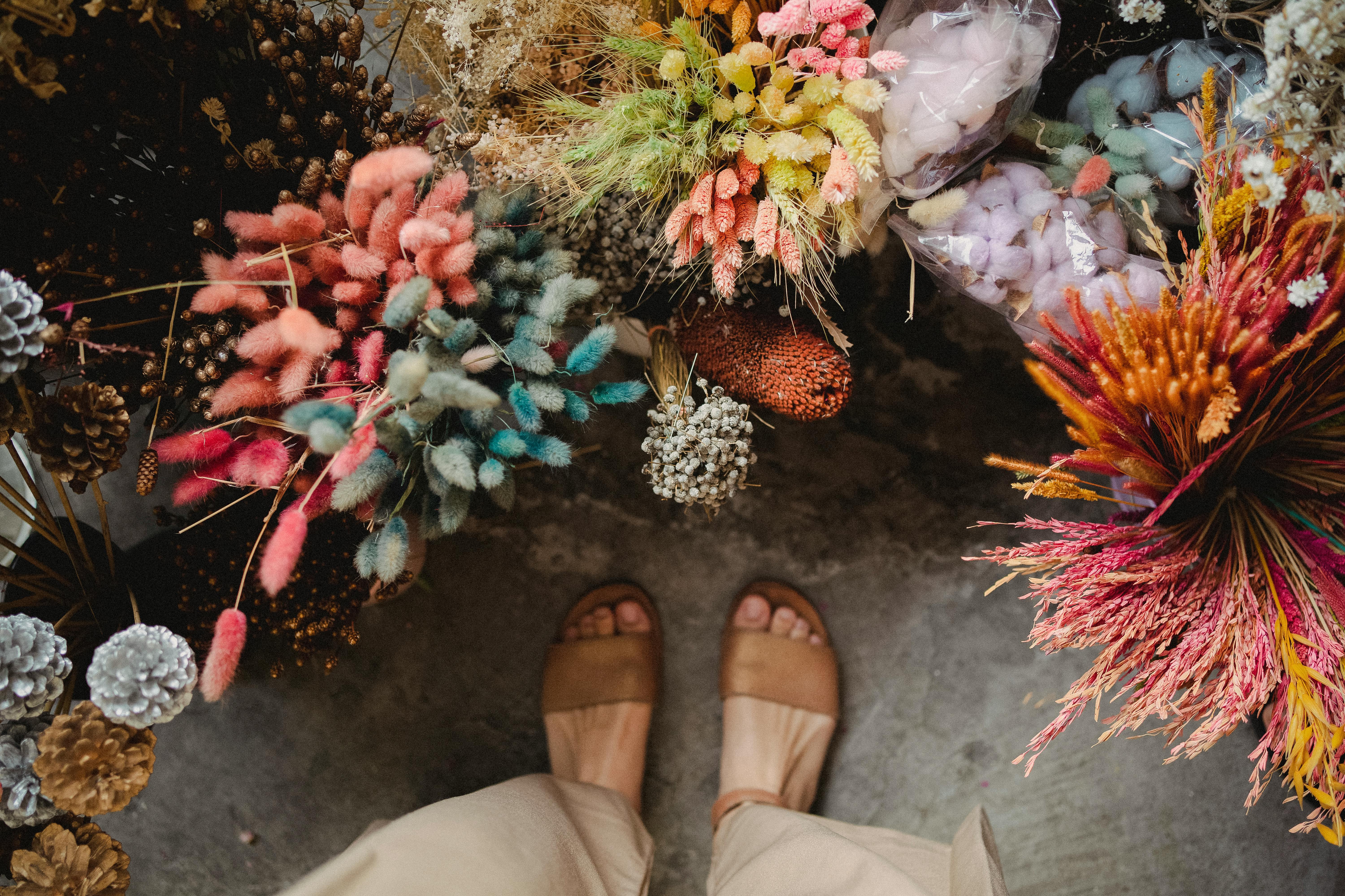 crop faceless woman standing near bright flowers in floral market