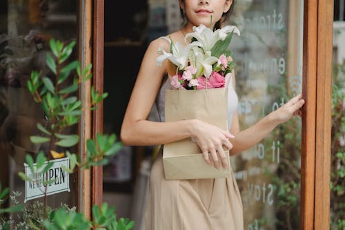 播种离开花卉商店的少妇与嫩花束