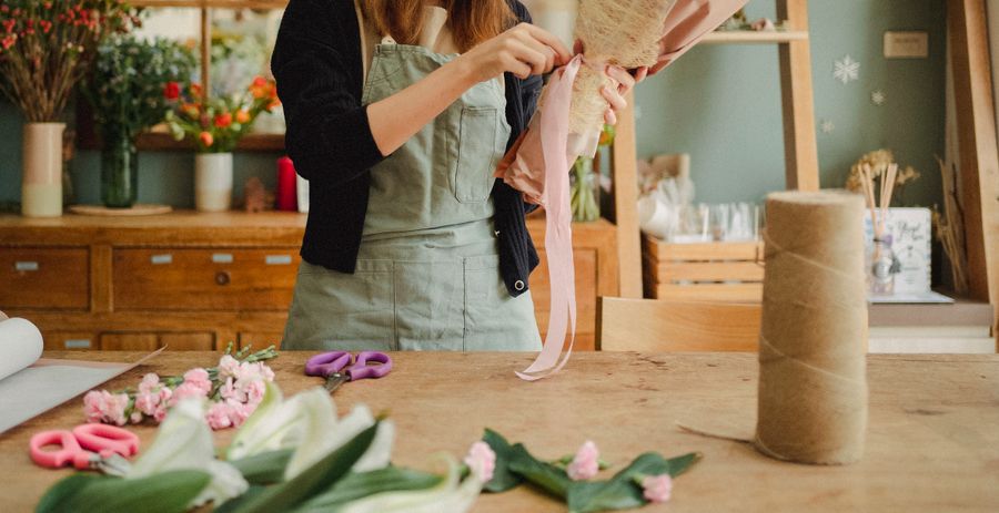 A florist wrapping a tulip bouquet at the workbench