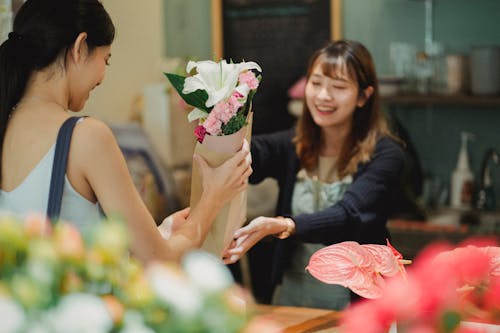 Free Happy Asian florist selling bouquet to female customer Stock Photo