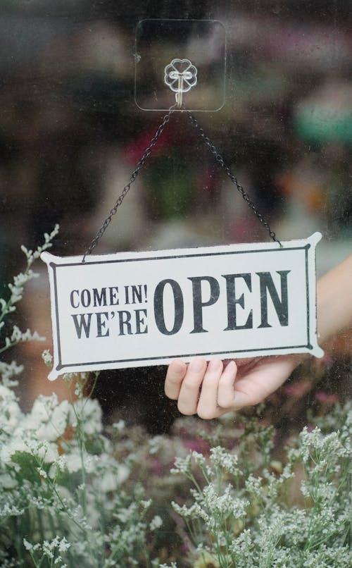 Free Crop faceless person turning shop signboard hanging on glass wall Stock Photo