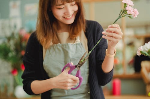 Урожай счастливый азиатский флорист срезает стебель цветка в цветочном магазине