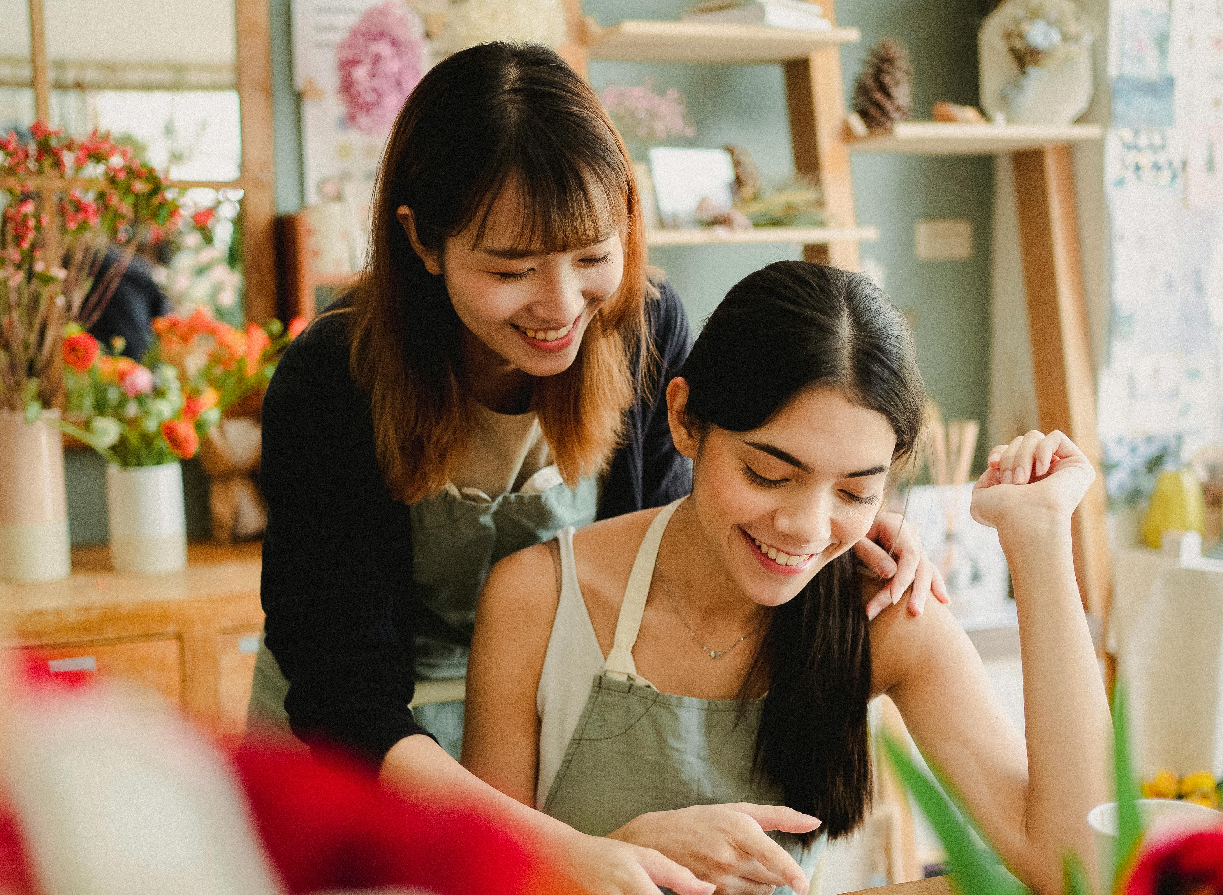 smiling florists working in floristry store in daytime