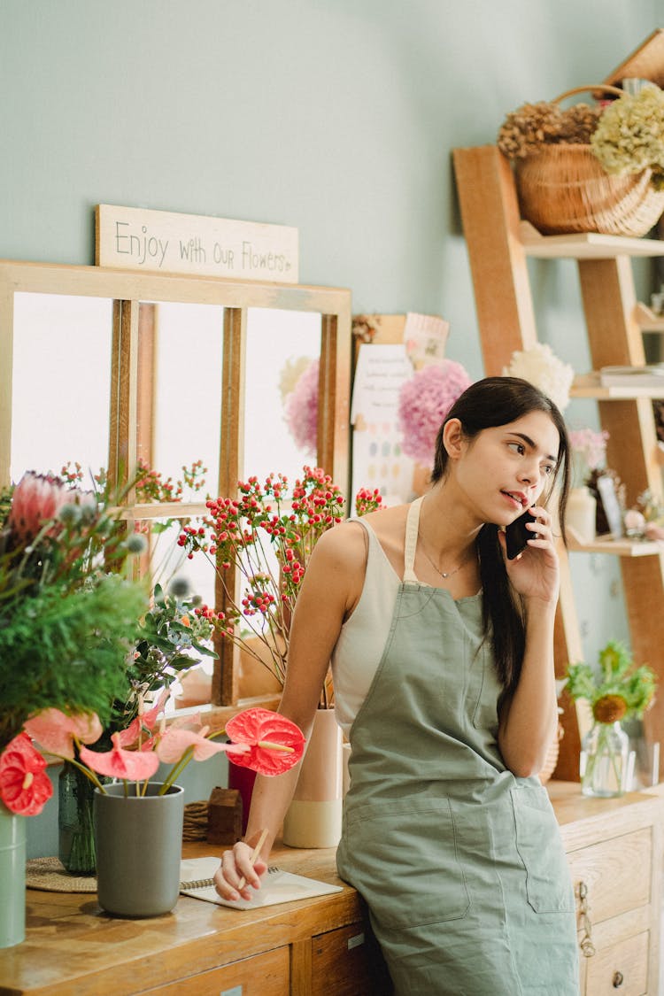 Pensive Florist Talking On Mobile Phone In Shop