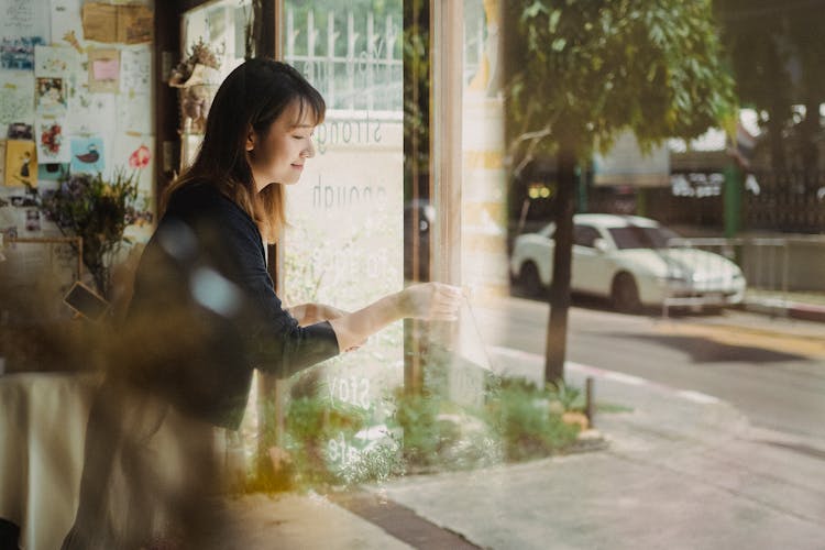 Though Glass Cheerful Asian Woman Opening Floral Store