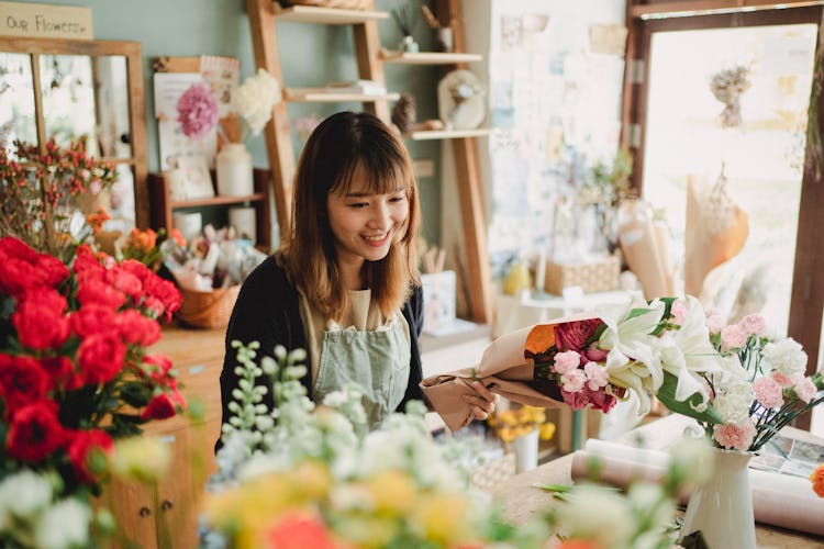 Happy Asian Florist Working In Cozy Floral Shop