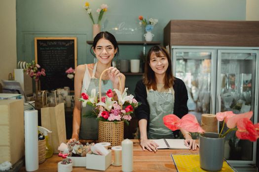 两位女花艺师在舒适的花店里微笑着，展示着充满活力的花束