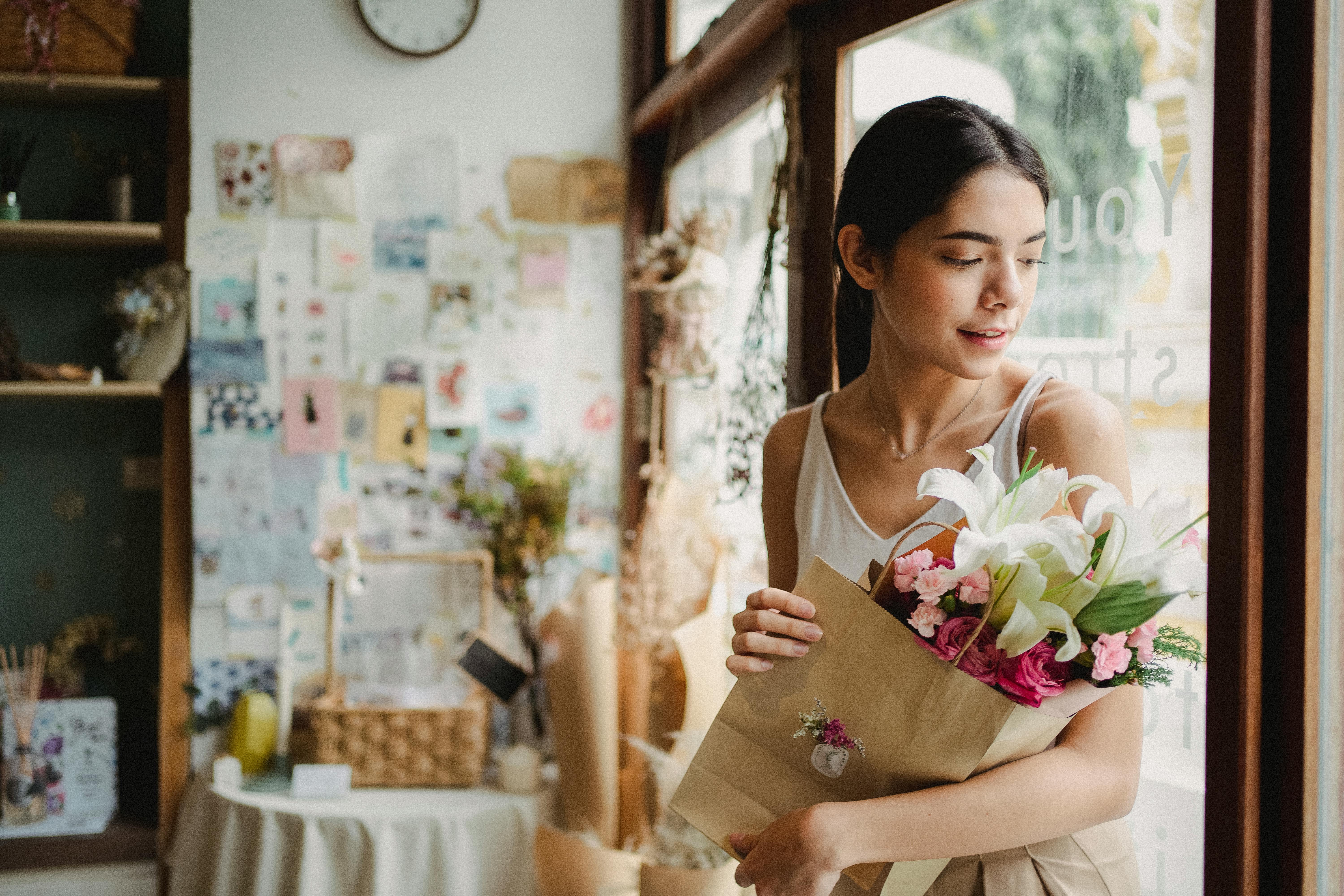 calm woman with bouquet of flowers standing near door in shop