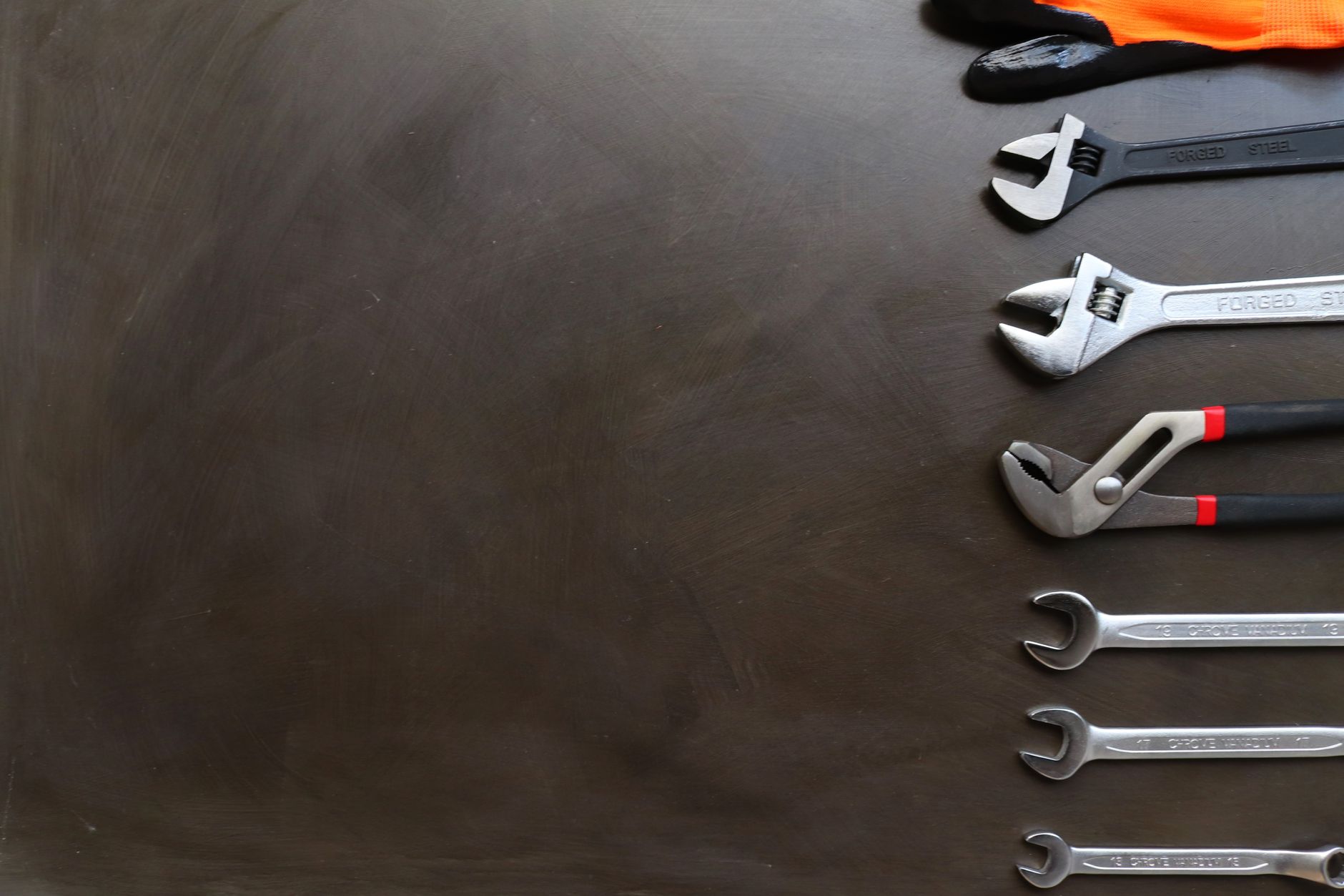 Assorted wrenches on a dark background with space for text. Ideal for industrial and tool-related design.