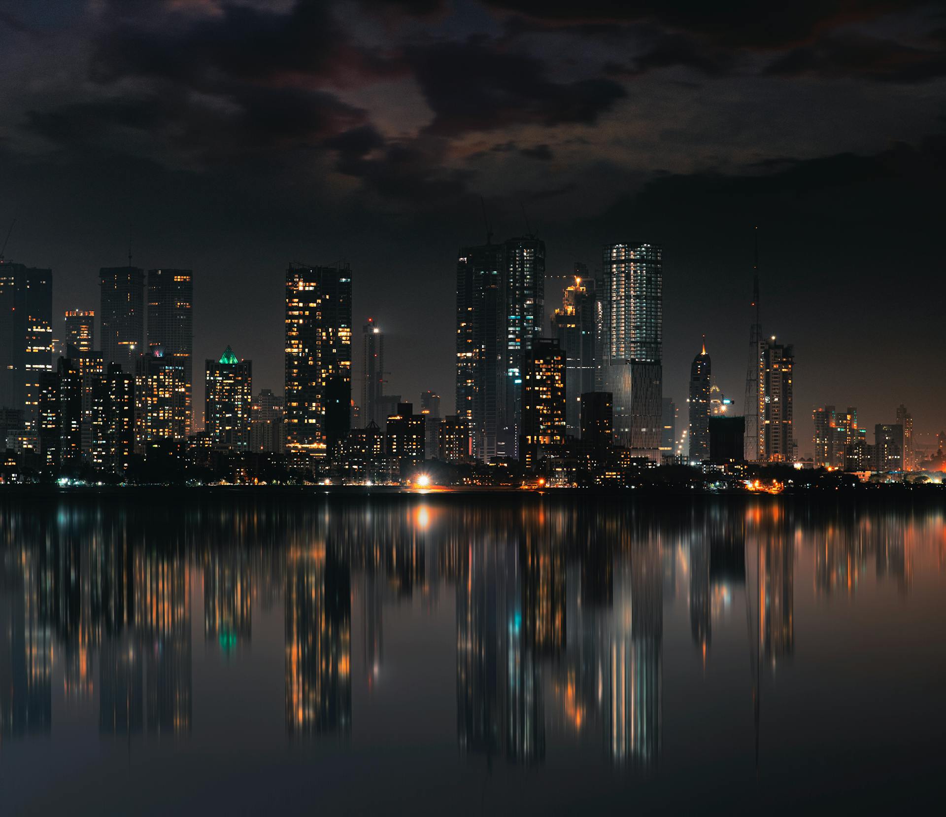 Captivating night view of Mumbai skyline with skyscrapers and reflections on still water.