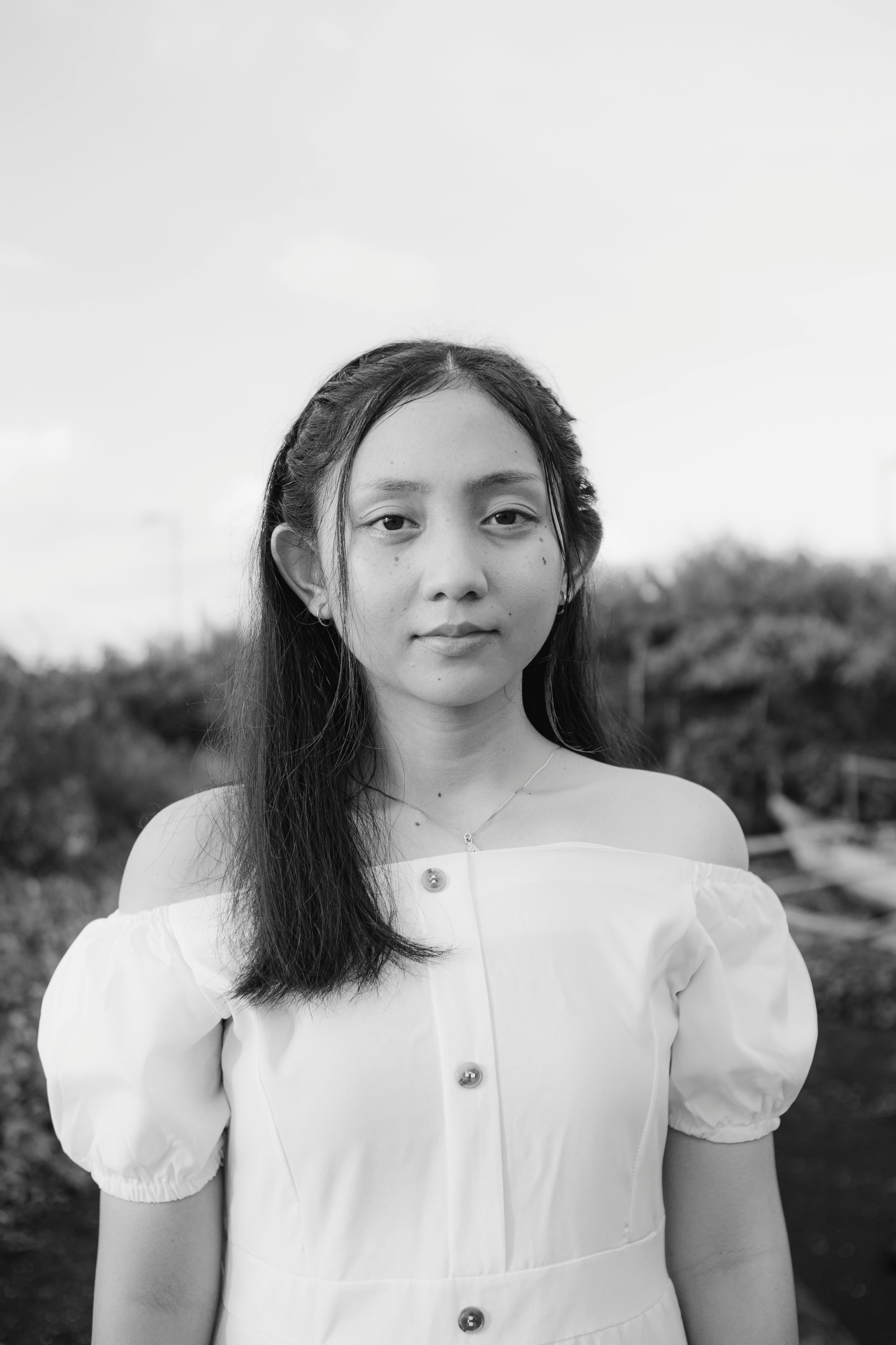 Serene black and white portrait of a young woman in a fashionable off-shoulder blouse.