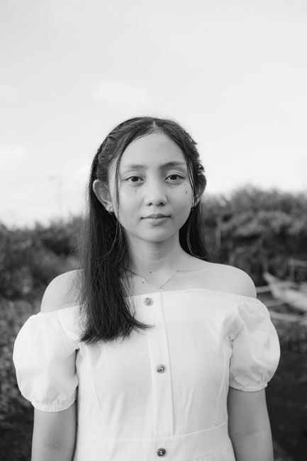 Serene black and white portrait of a young woman in a fashionable off-shoulder blouse.