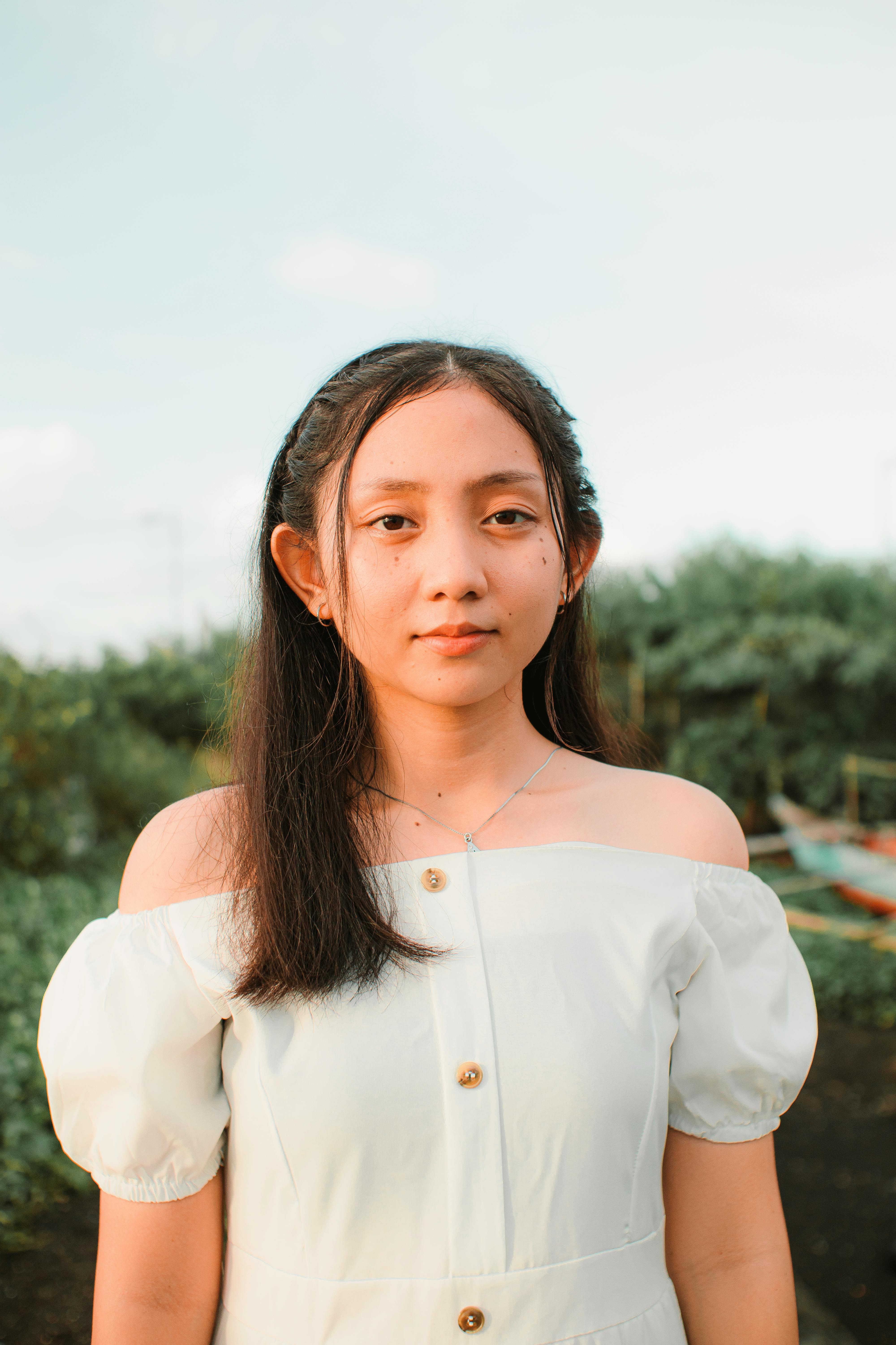 elegant asian adolescent behind trees in summer