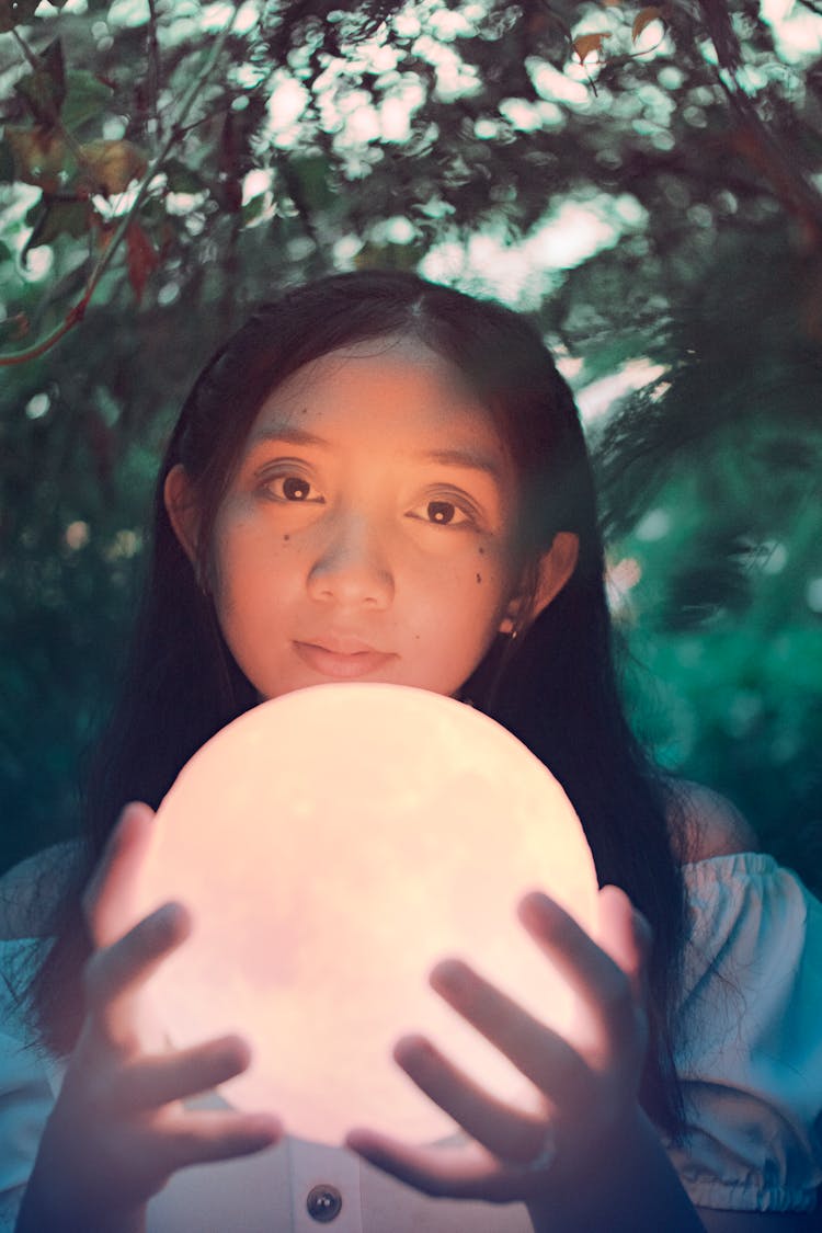 Charming Ethnic Female Teenager With Glass Ball In Garden