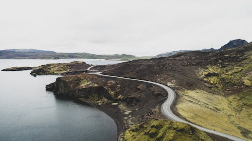 An Aerial Photography of a Road on Mountain Near the Body of Water