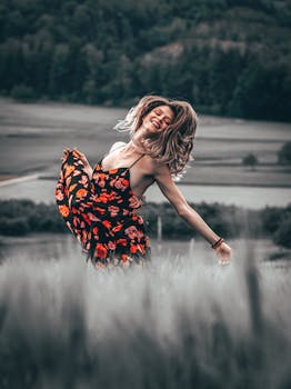 在瑞士的户外，一名女子穿着花卉连衣裙，在风景如画的田野中快乐地跳舞