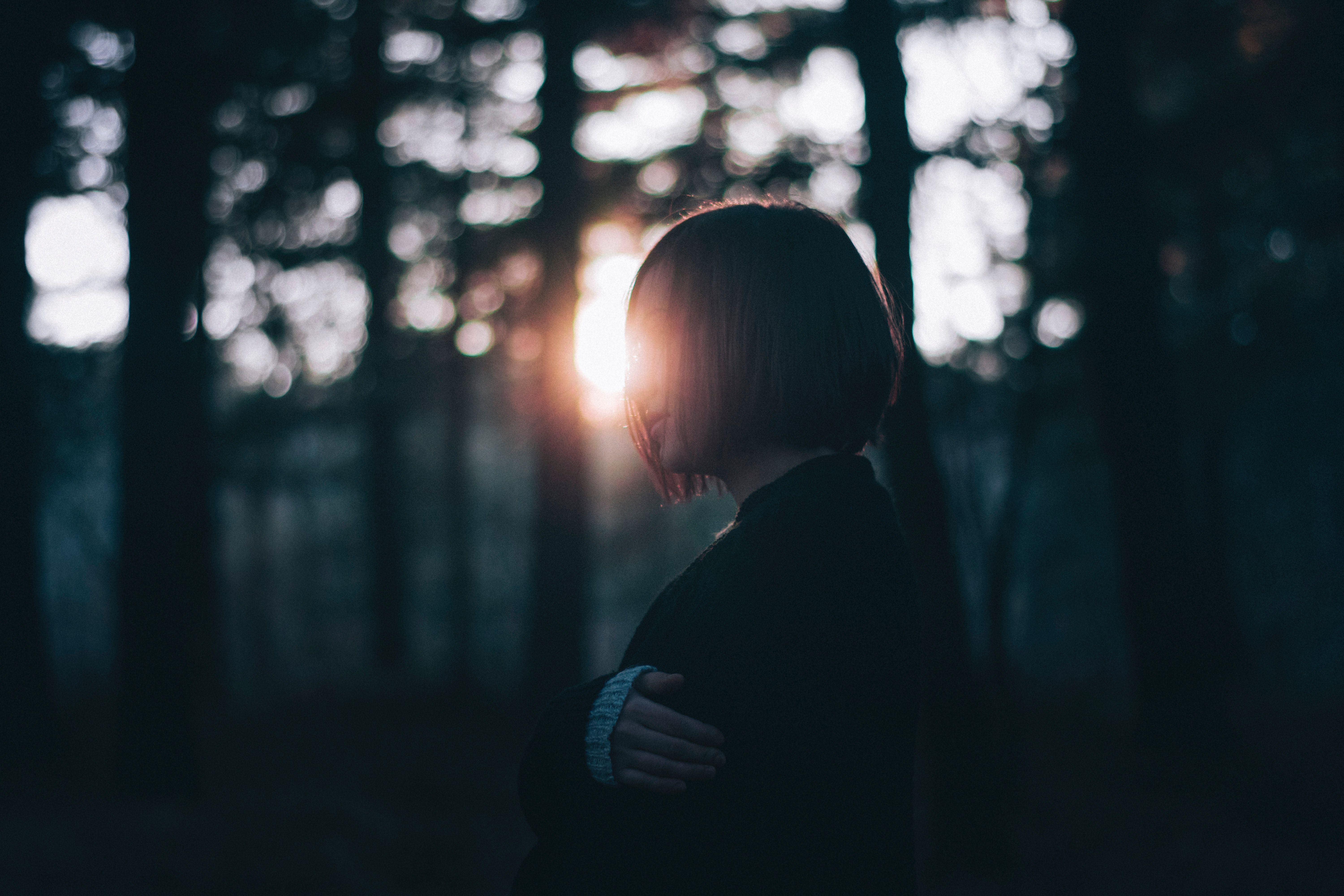 Silhouette of a woman in a serene forest at sunrise, capturing tranquility