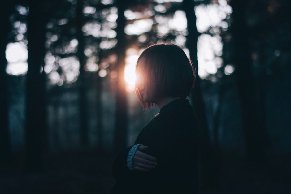 Silhouette of a woman in a serene forest at sunrise, capturing tranquility