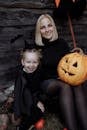 一对快乐的母女穿着戏服，用雕刻的南瓜庆祝万圣节
