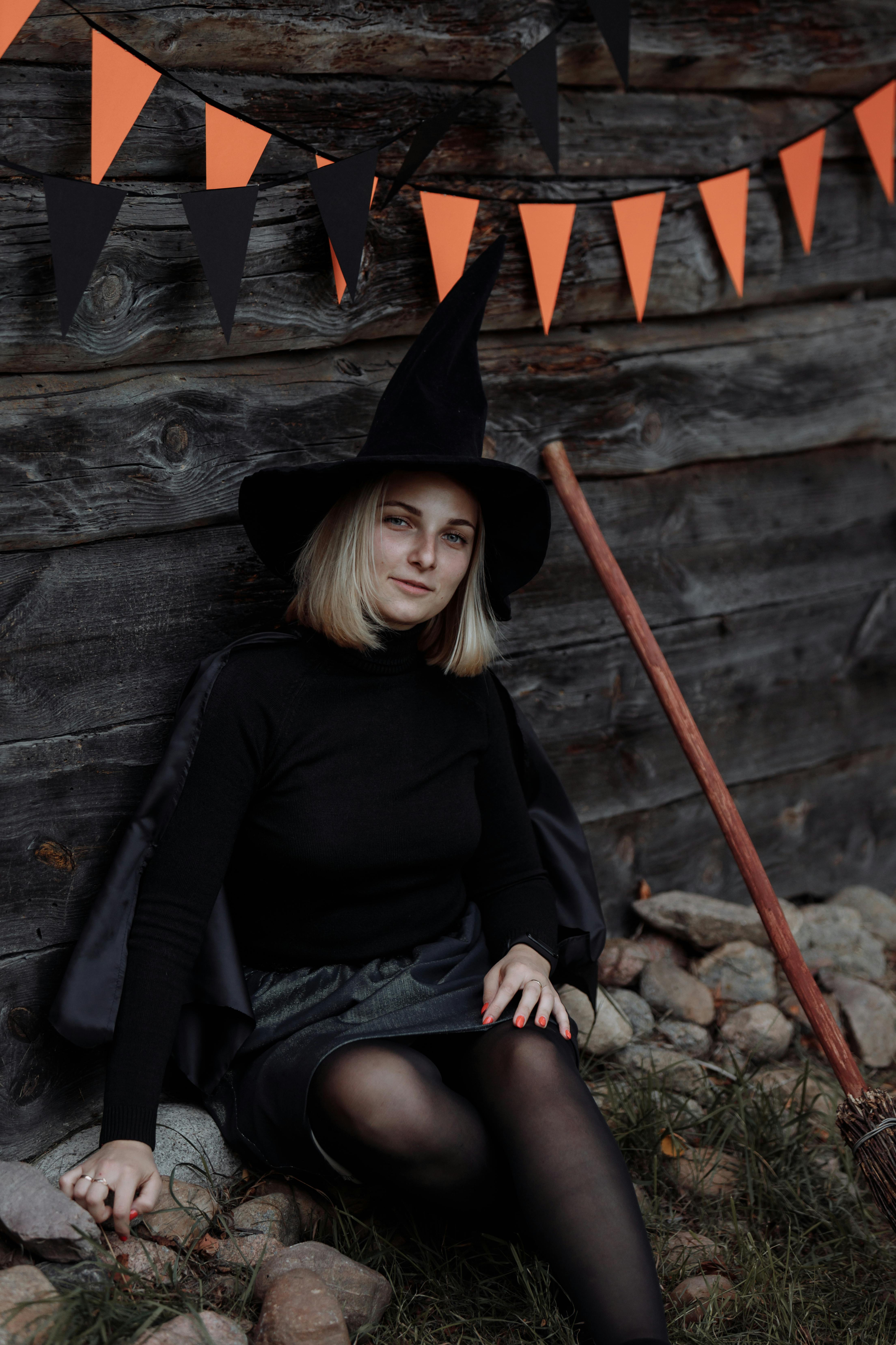 woman in black long sleeve shirt and black hat sitting on brown wooden fence