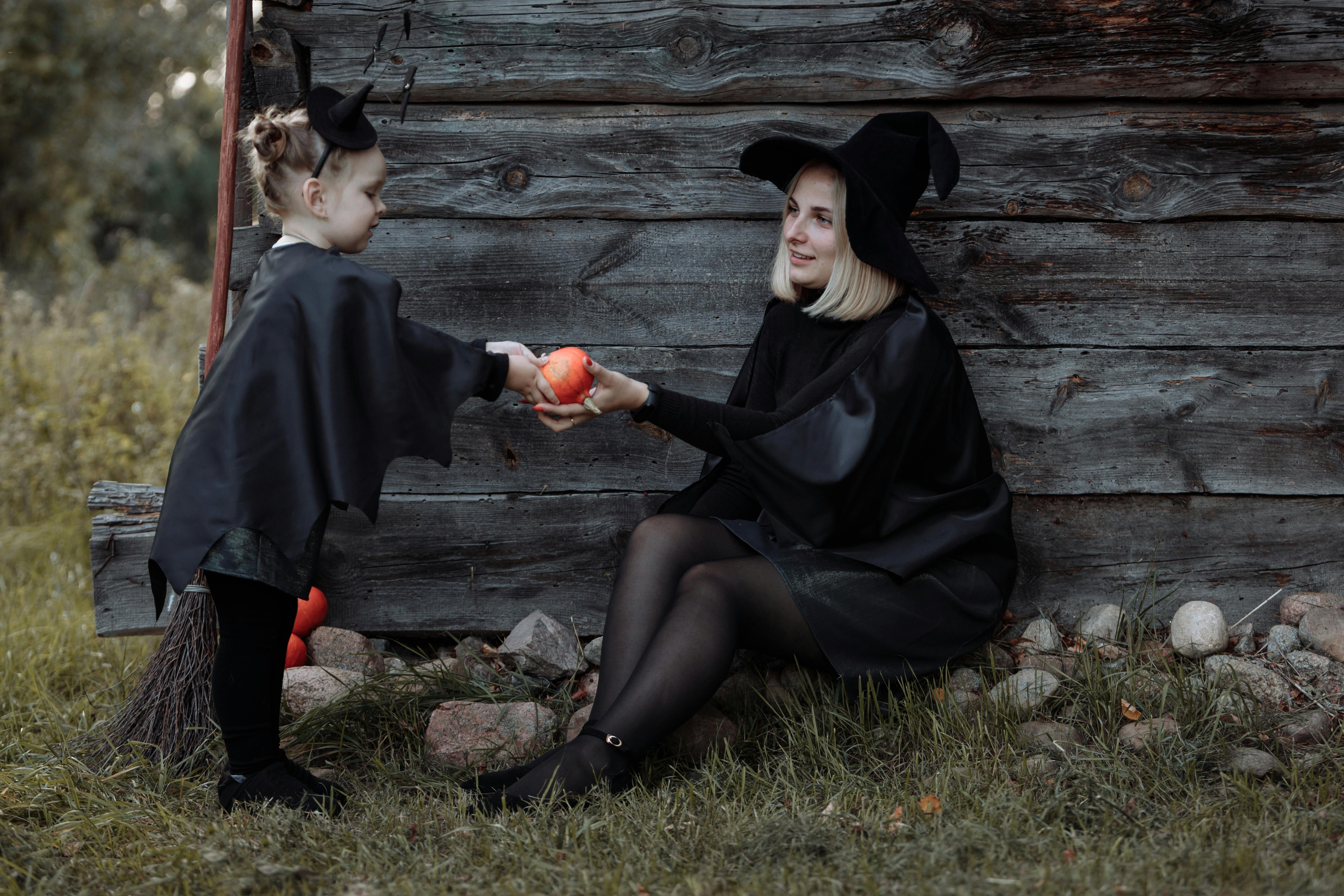 在户外万圣节庆祝活动中，一对打扮成女巫的母子共享了一个温馨时刻