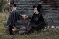 在户外万圣节庆祝活动中，一对打扮成女巫的母子共享了一个温馨时刻