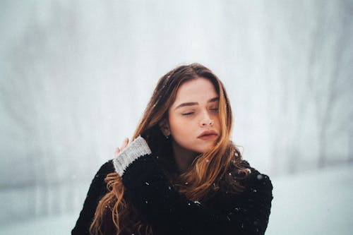 Portrait of a Young Woman Holding Her Hand in Hair Outdoors in Winter 