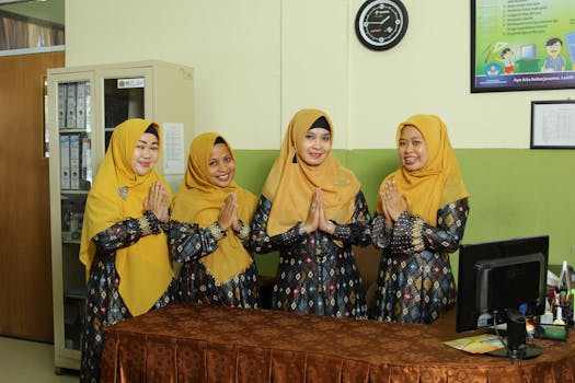 Indonesian female teachers in traditional dress standing indoors, showcasing cultural clothing.