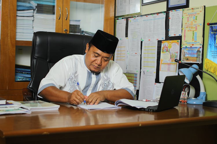 School Principal Filling Out Documents In His Office