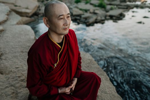 一位佛教僧人在平静的河边宁静地冥想，体现了宁静与灵性