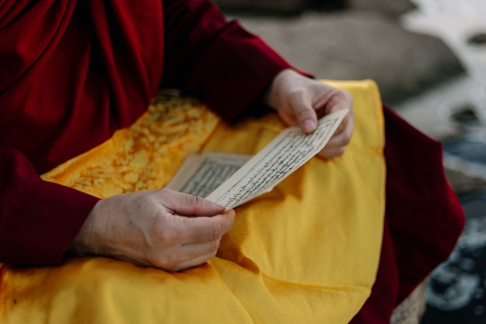 Person reading a sacred text closely, hands visible, representing the study and self-inquiry central to jnana yoga