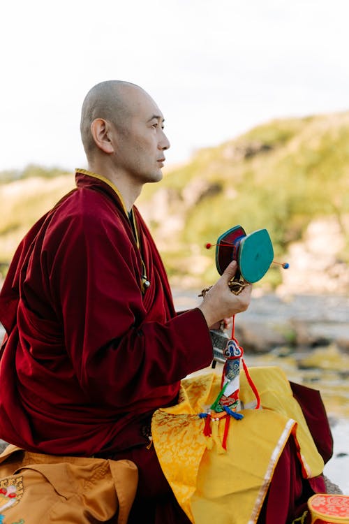 A Monk in Red Robe Holding a Wooden Prayer Wheel