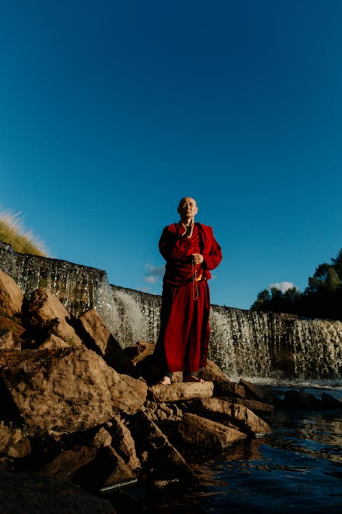 Bald man Standing on Brown Rock