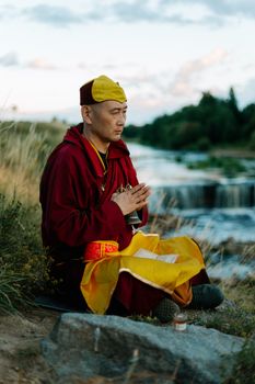 一位身着传统服装的僧侣，正坐在宁静的瀑布旁进行户外冥想