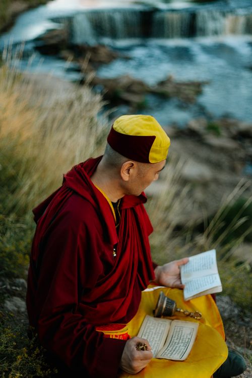 Free Buddhist monk in meditation by a serene river surrounded by nature. Stock Photo