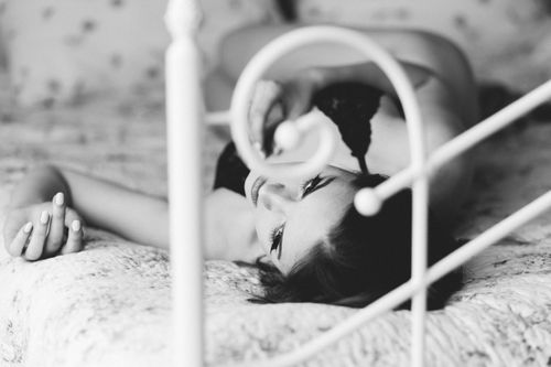 Free A captivating black and white portrait of a woman lying on a bed, showcasing elegance and beauty. Stock Photo