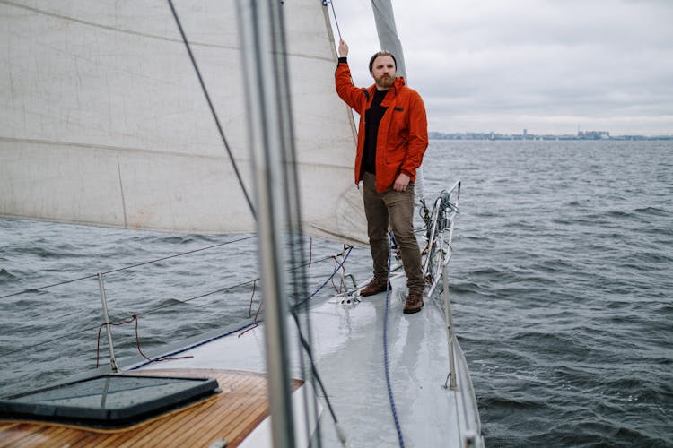 Man Wearing A Jacket And Jeans Standing On Boat