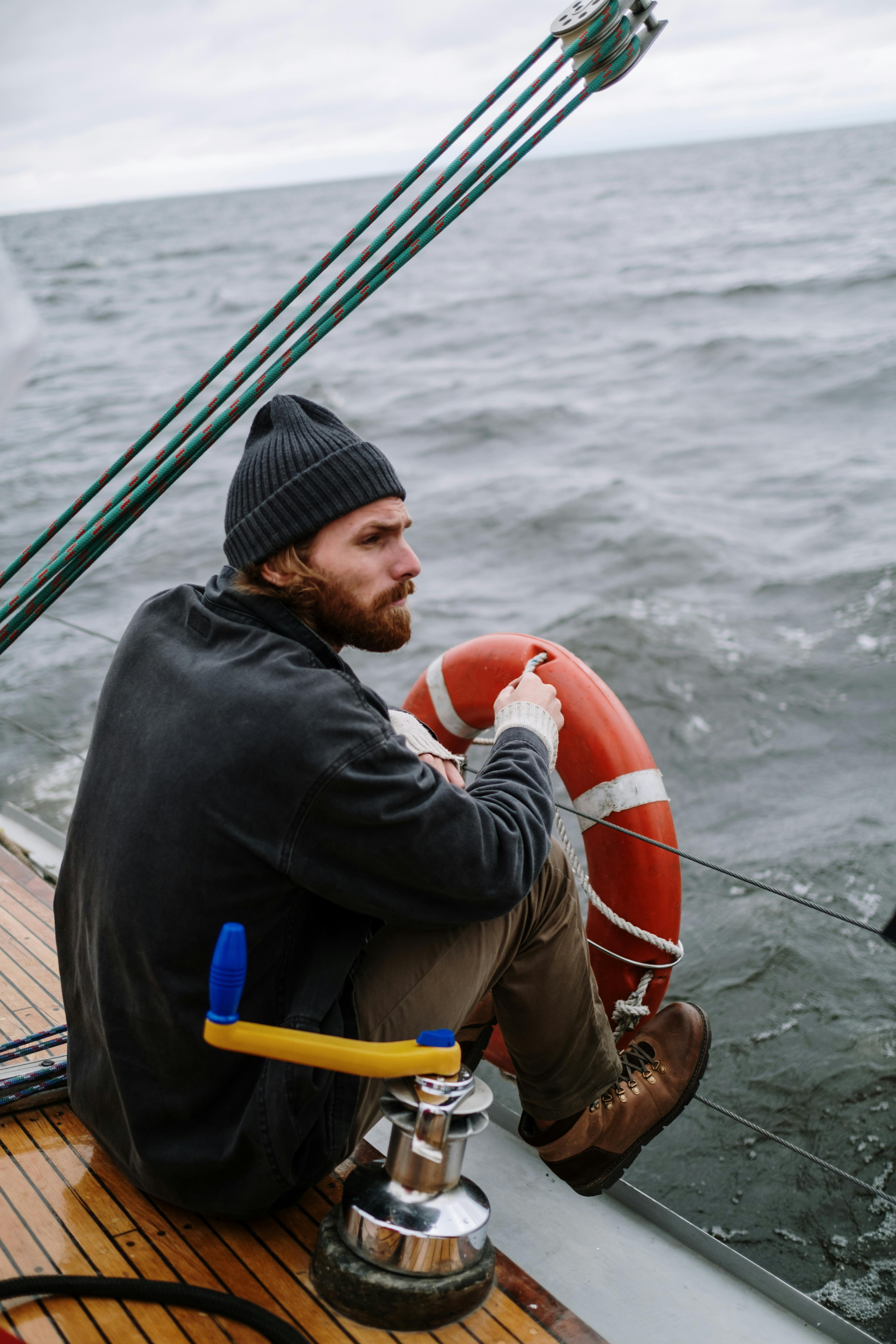 Man in Black Hoodie Standing Beside the Metal Railing of a Boat