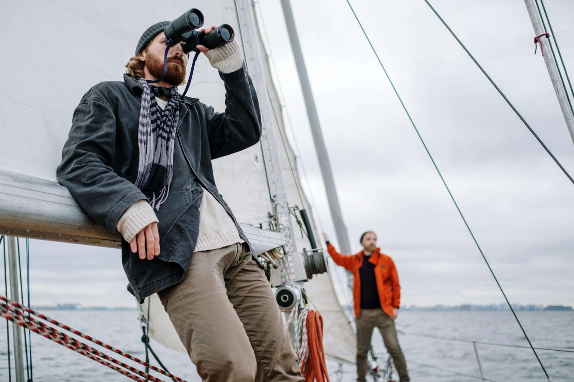 Sailor Looking Around Through Binoculars from the Deck of a Sailboat