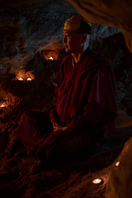 岩の上に座っている赤いローブの男