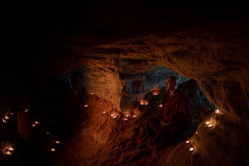 Tibetan Monk Meditating in a Cave Lit by Candles