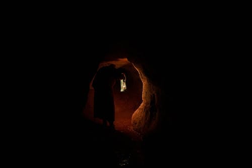 A Person Holding a Lamp in a Dark Cave