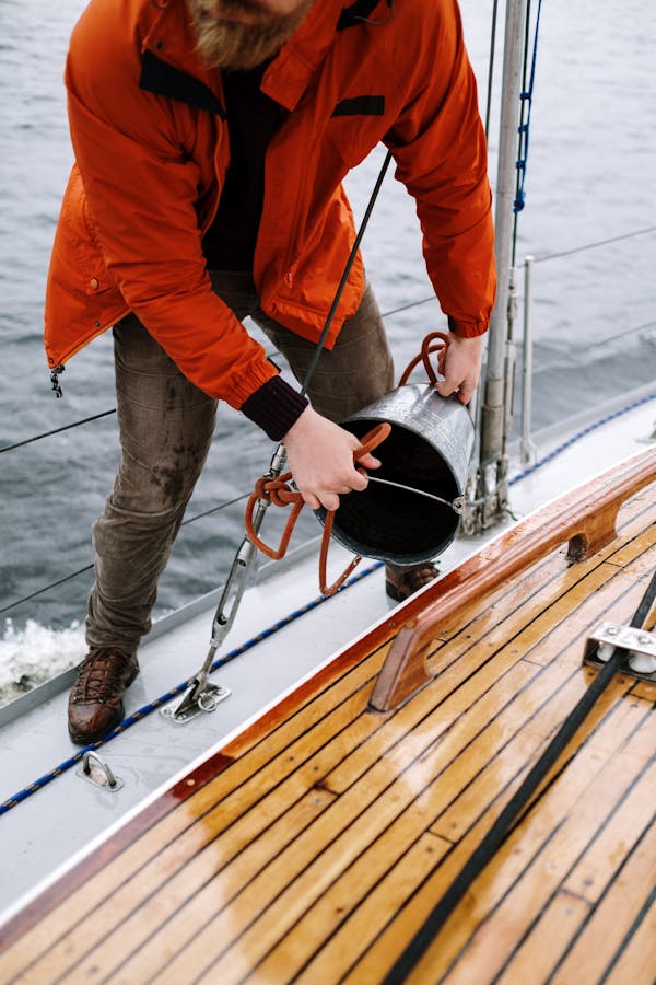 Man in Orange Jacket and Gray Pants Holding Black and Red Fishing Rod