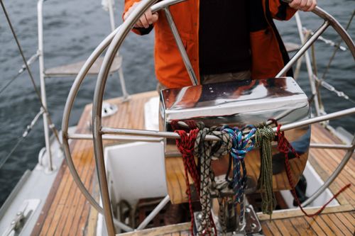 Free Close-up of a sailor holding the helm of a sailboat, navigating the open sea. Stock Photo