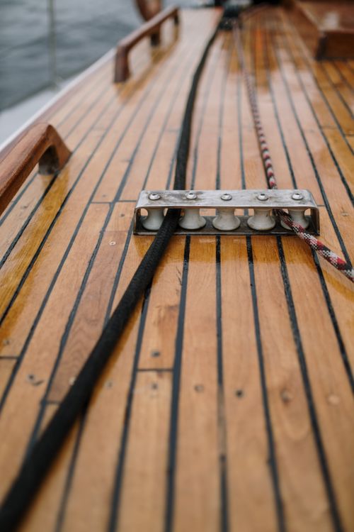 Free A detailed view of a wet sailboat deck featuring ropes and wooden planks. Stock Photo