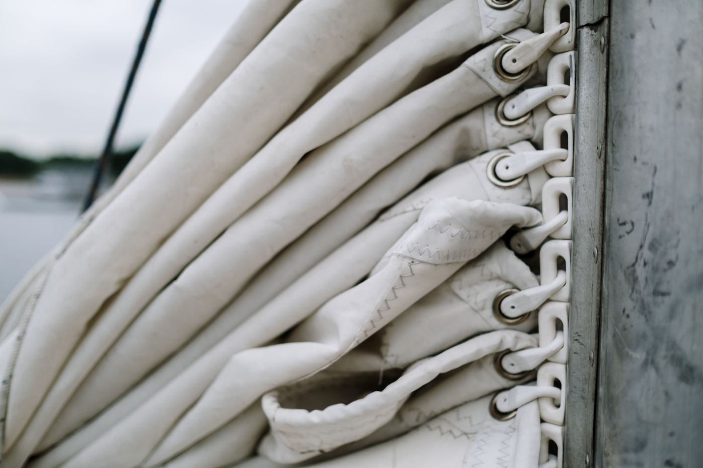 Folded sail canvas stacked along a boom, hand-set grommets down the edge — photo by cottonbro studio on Pexels
