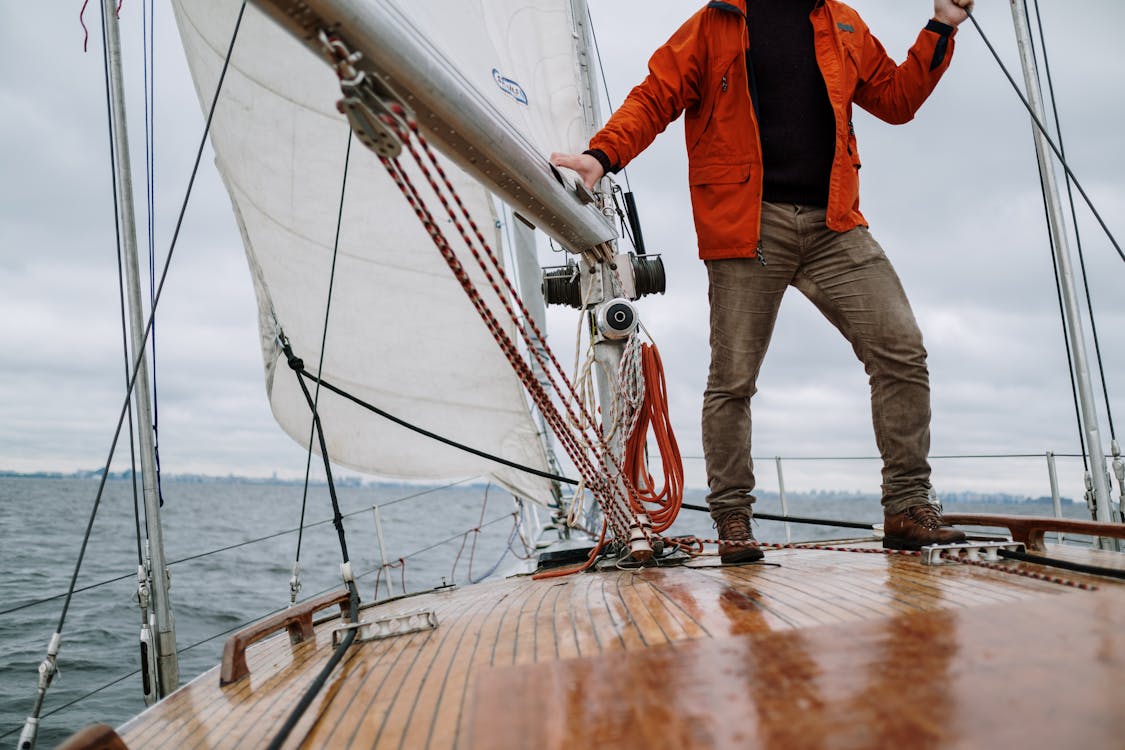 Free Man in Red Jacket and Brown Pants Standing on Brown Wooden Dock Stock Photo