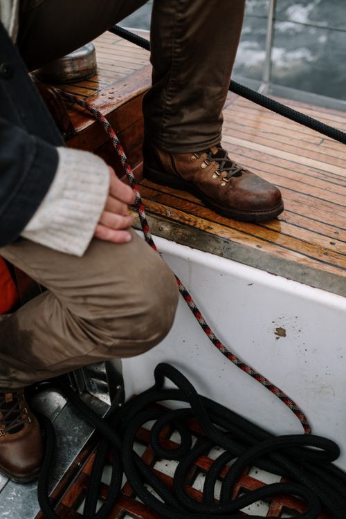Free Close-up of a crew member standing on a yacht deck with ropes and water visible. Stock Photo