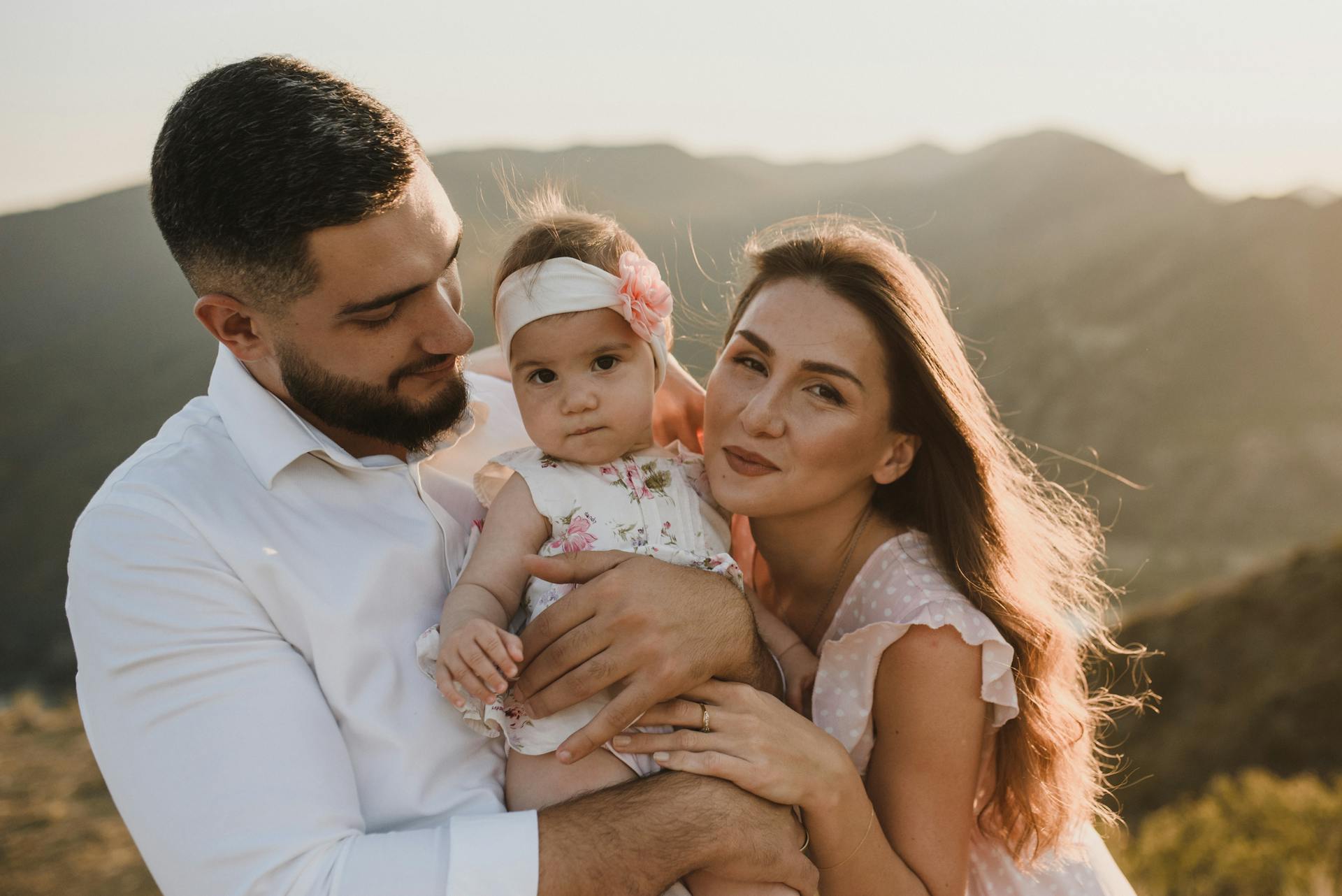 Loving family portrait outdoors with scenic mountain background at sunset.