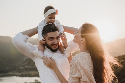 A joyful family moment with parents holding their baby outdoors at sunset.